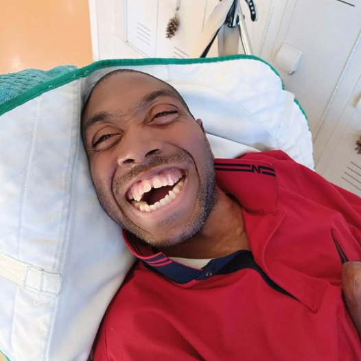 A man laying down smiling up towards the camera
