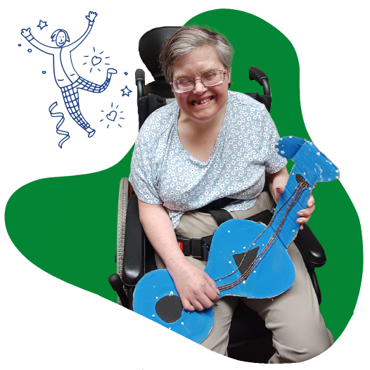 A woman in a wheelchair holding a paper guitar
