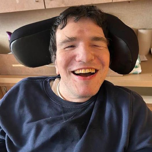 A man in a wheelchair leaning back and smiling
